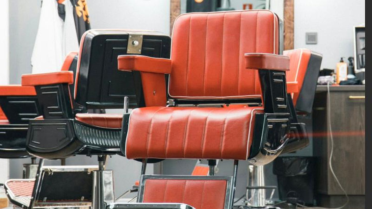 Reihe roter Barber-Ledersessel im Salon vor Spiegeln mit Gl&uuml;hbirnen im Retro-Look