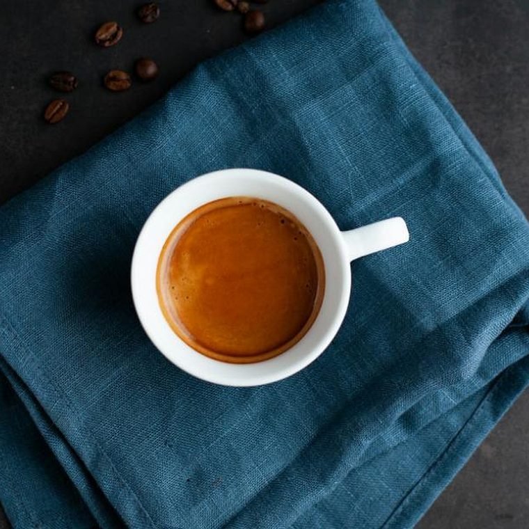 Einzelne Tasse Espresso aus eigener Röstung auf einem blauen Leinentuch