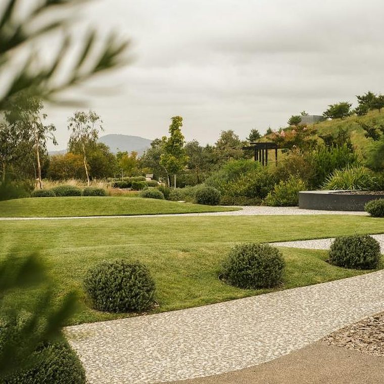 Gestaltete Gartenanlage mit geschwungenem Kiesweg, Rasenflächen und runden Formgehölzen