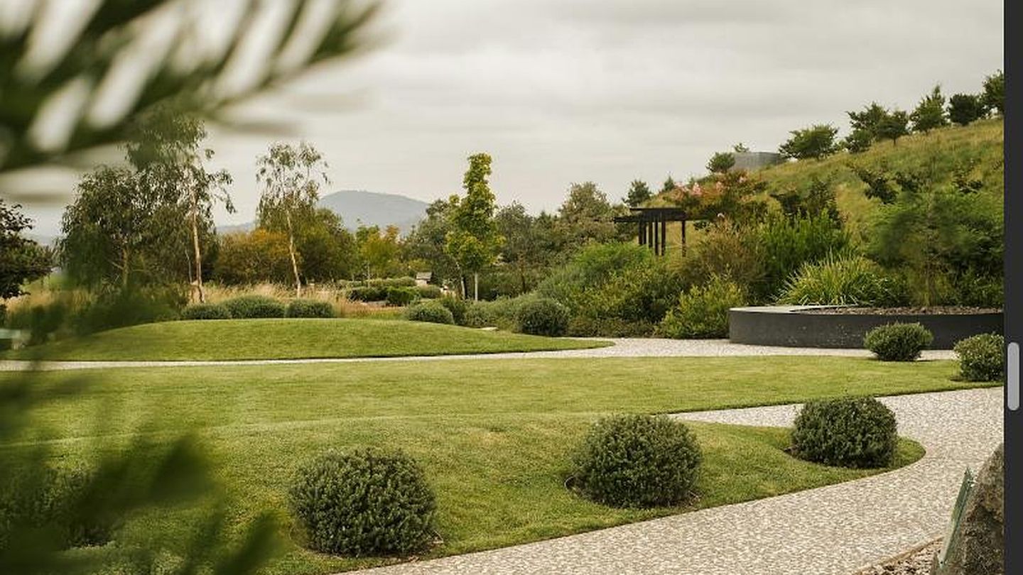 Angelegter Hausgarten mit gepflegtem Rasen, geschwungenen Staudenbeeten und Natursteinweg