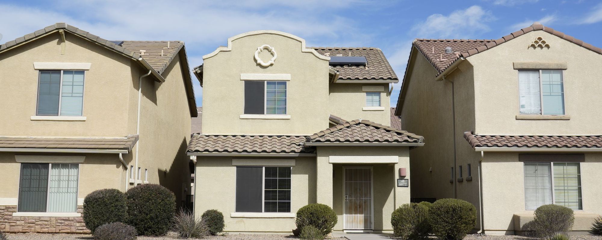 Row of stucco houses with tile roofs under a blue sky in Arizona