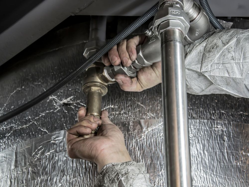 Hands tightening a fitting on a pipe