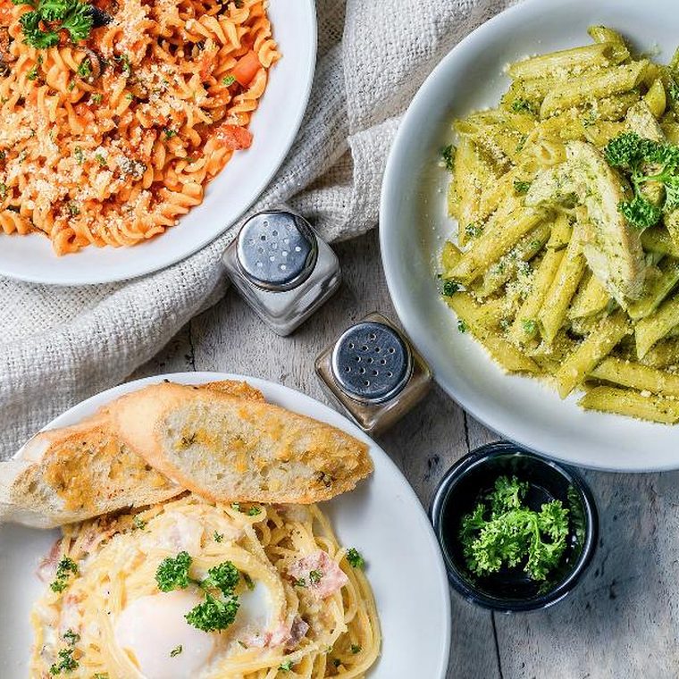 Drei Pastagerichte von oben: Fusilli in Tomatensauce, Penne mit Pesto und Carbonara mit Brot