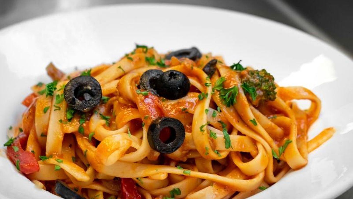Angerichteter Teller Tagliatelle in Tomatensauce mit schwarzen Oliven und Brokkoli