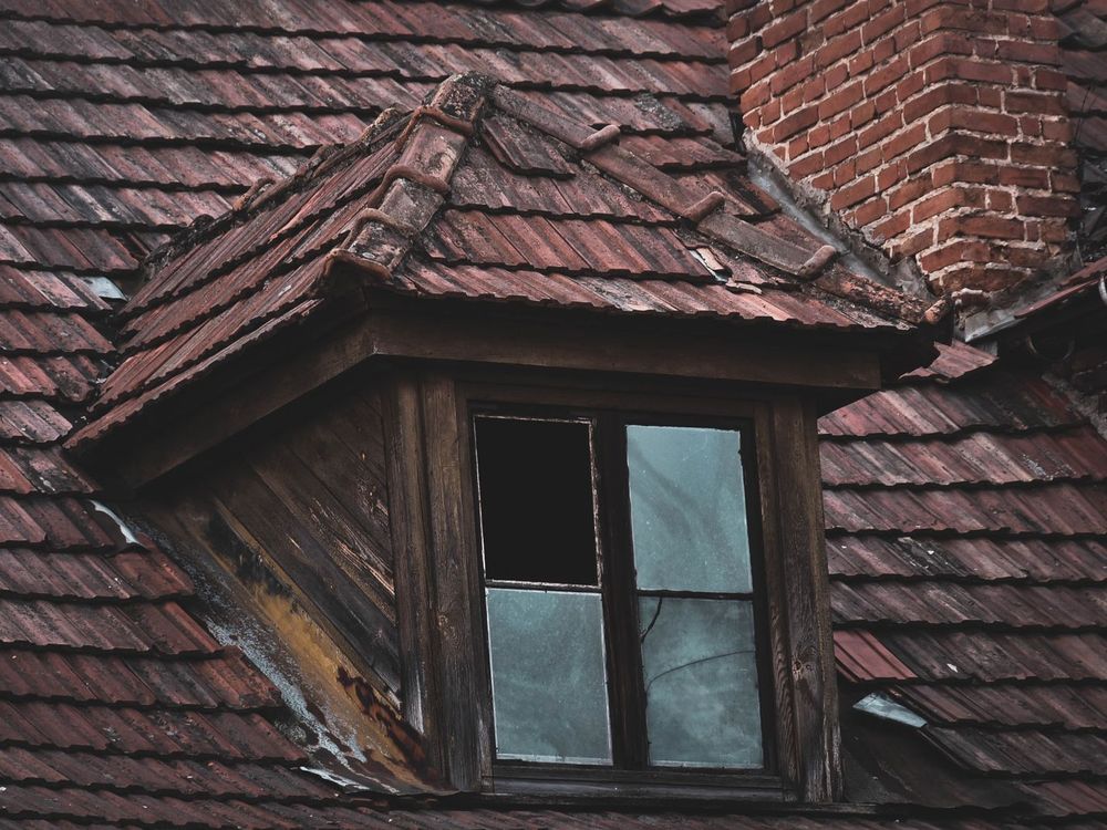 Weathered old roof around a dormer window