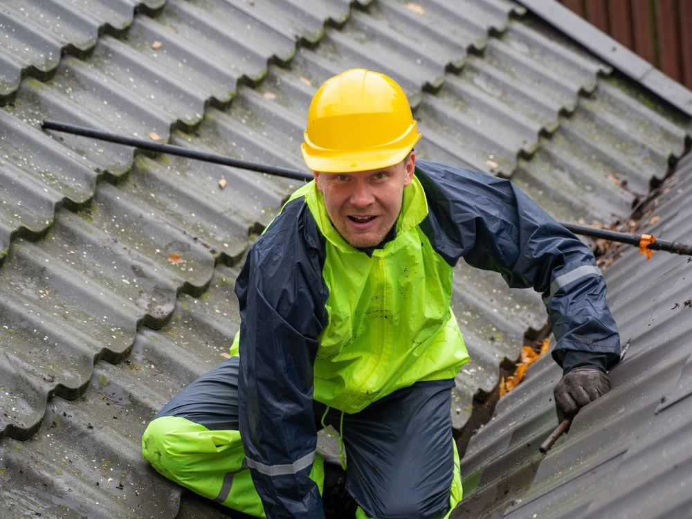 Roofer wearing a hard hat and safety harness on a pitched roof