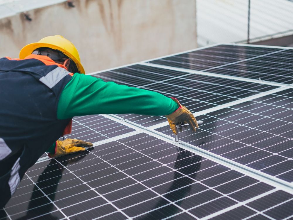 Installer in a hard hat fixing a solar panel