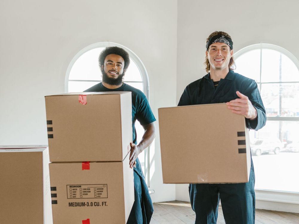 Zwei Möbelpacker mit Kartons in einer hellen Wohnung