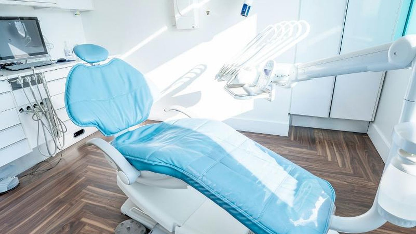 Wohnlich wirkendes Behandlungszimmer mit hellblauem Stuhl, Fischgrätparkett und viel Tageslicht
