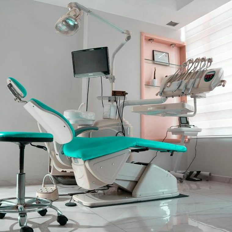 Behandlungszimmer mit mintgrünem Behandlungsstuhl und Hocker vor einer rosafarbenen Wandnische