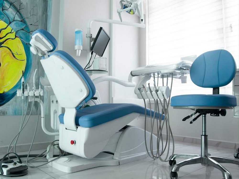 Blauer Behandlungsstuhl mit Instrumenten und Monitor für die digitale Implantatplanung